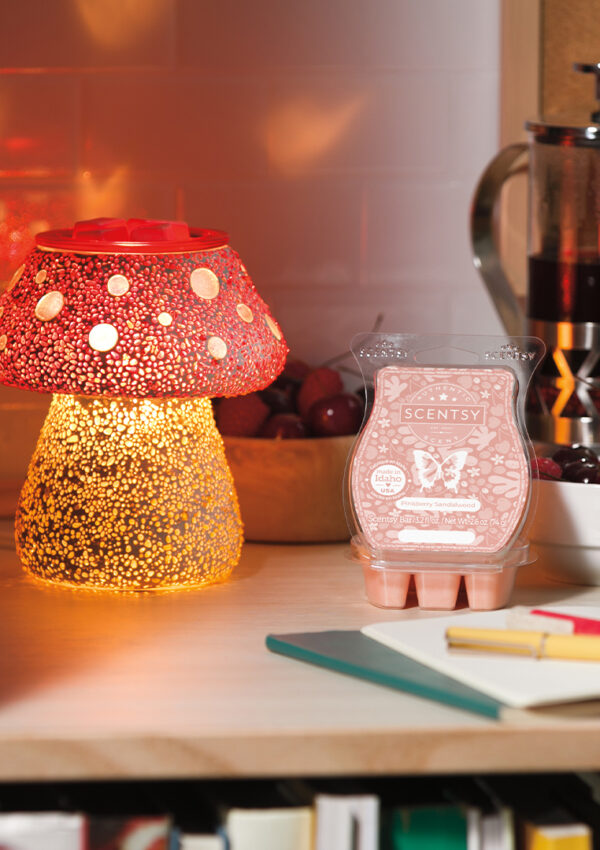 A desk with a notebook and pencil, scentsy wax, and scentsy warmer glowing in the corner.