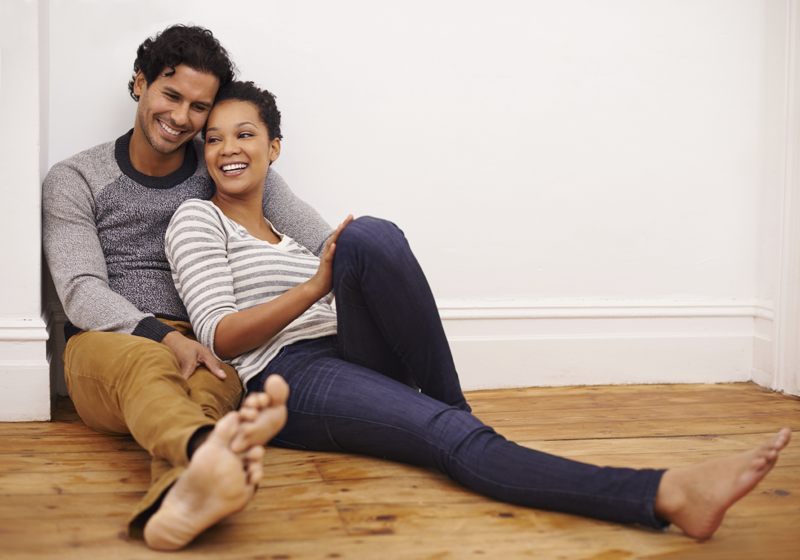 Cropped shot of an affectionate young couple sitting on the floor in their living room