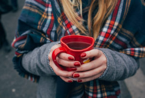 person holding a warm cup of coffee in heart mug