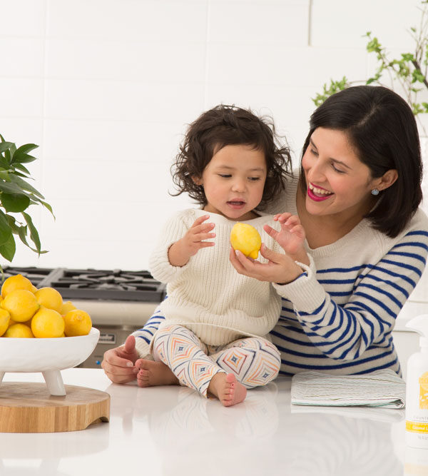 Mother holding child in Kitchen next to Scentsy Clean products