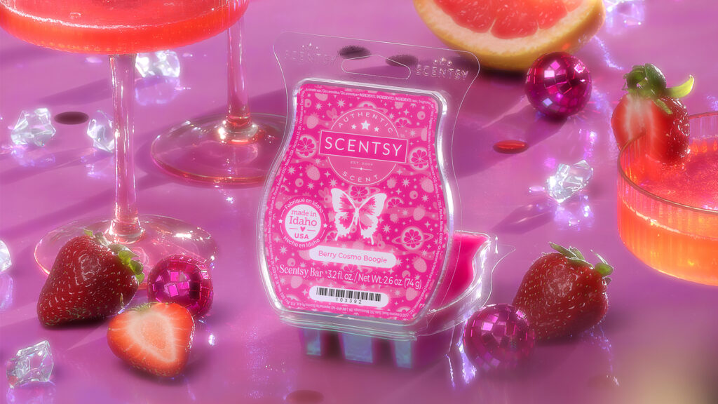 Scentsy's Berry Cosmo Boogie Wax Bar sit's on a bright purple tabletop with it's fushia colored clamshell lid open. Strawberries, purple disco ball party decor, and sunburst orange cocktails in long-stemmed glasses surround the wax bar amidst gleaming ice cubes.