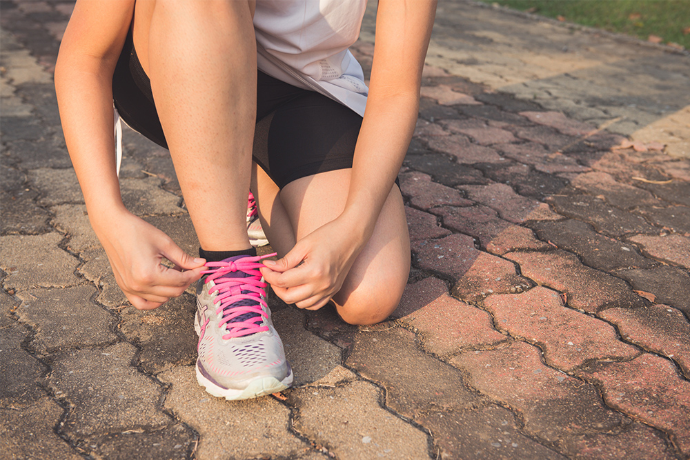 photo of woman putting on running shoes