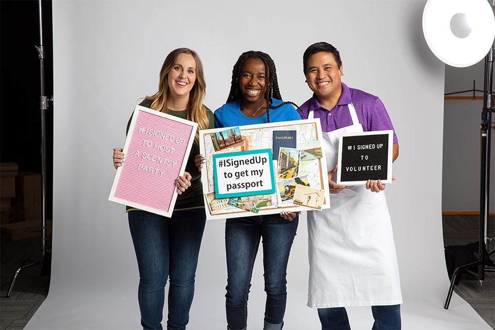 Photo of diverse consultants proudly holding signs showcasing what they have signed up