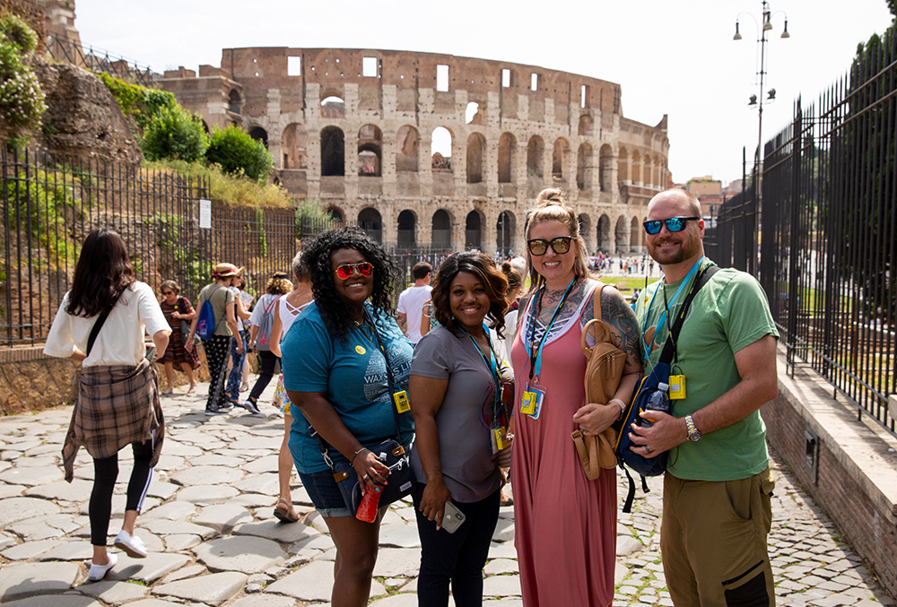 consultants pose and smile on in front of the colosseum in Rome, Italy