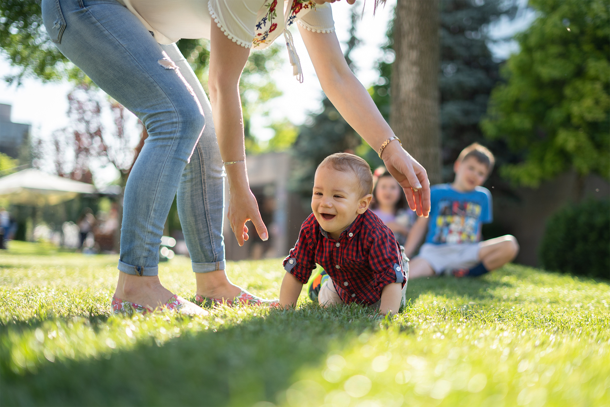 mother picking up sun crawling in sunny yard