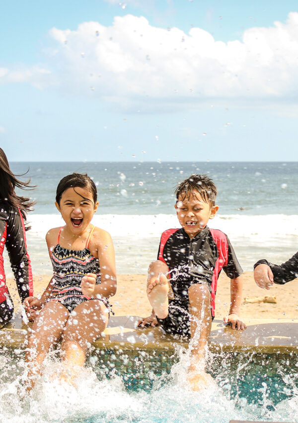Mother and her children laughing on a surf board in the ocean waves