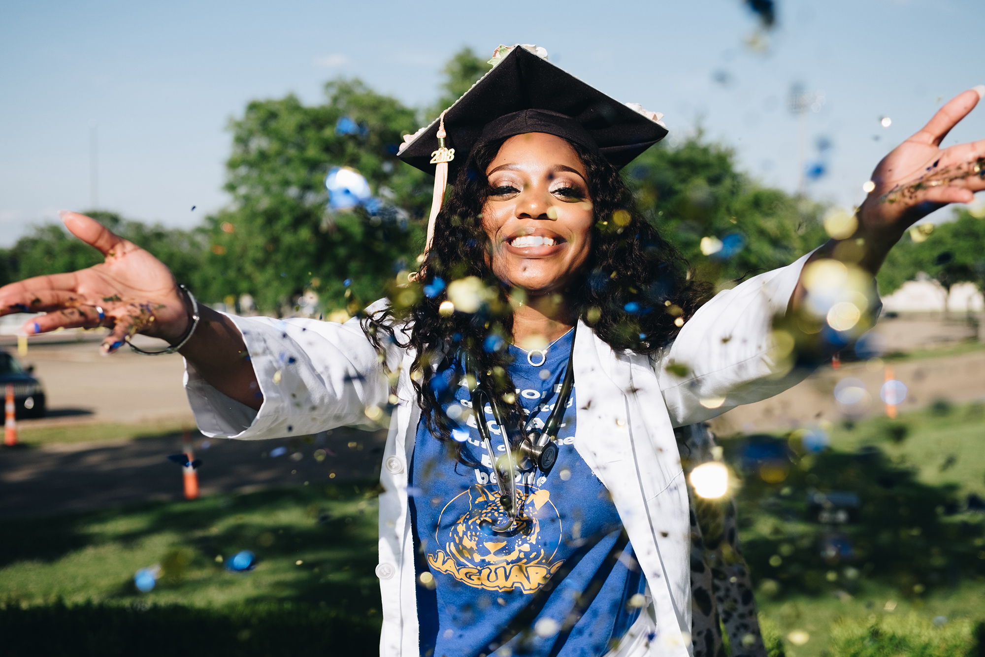 happy graduate throwing glitter in her regalia