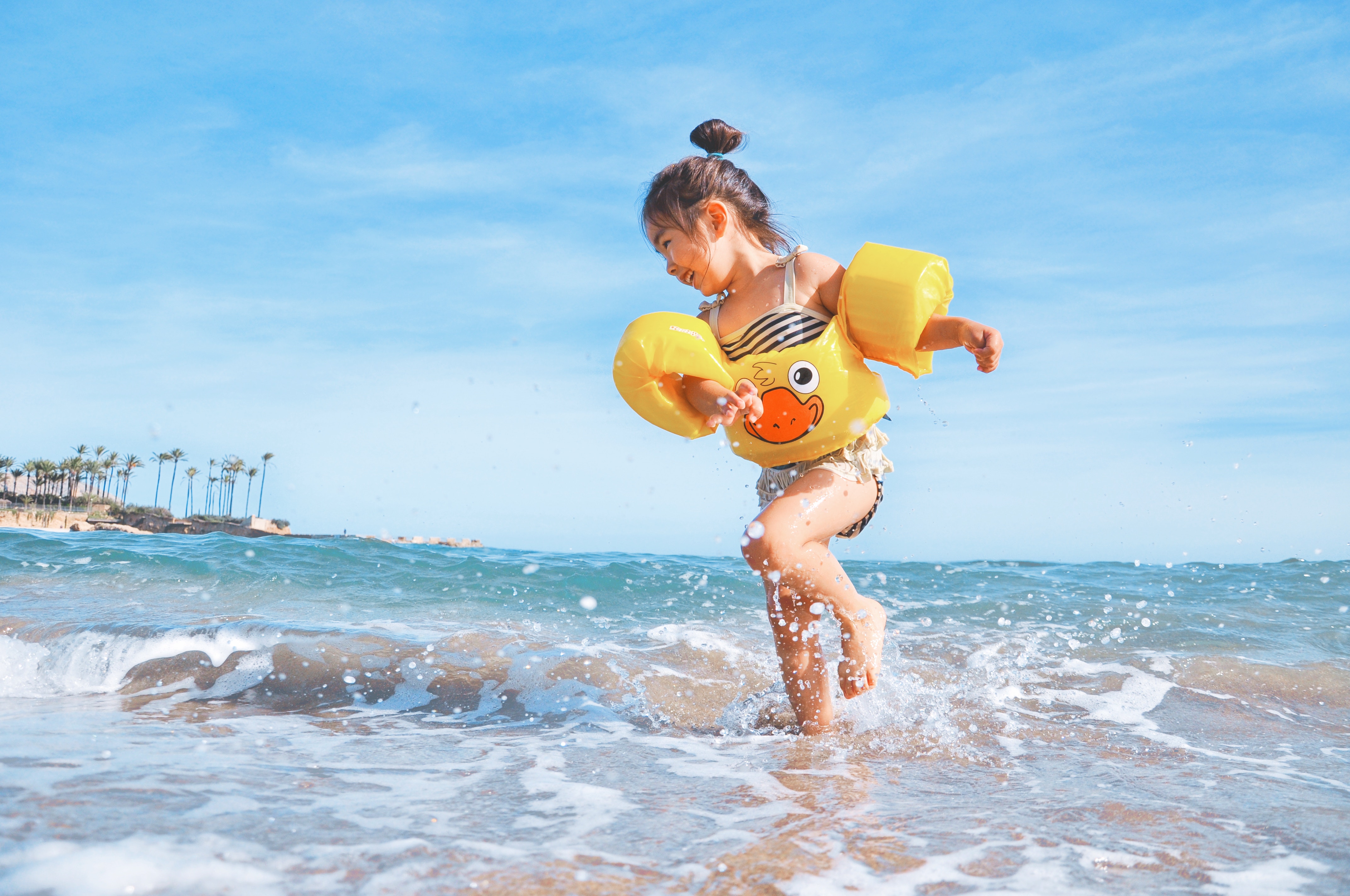 Little girl laughing while running in ocean waves