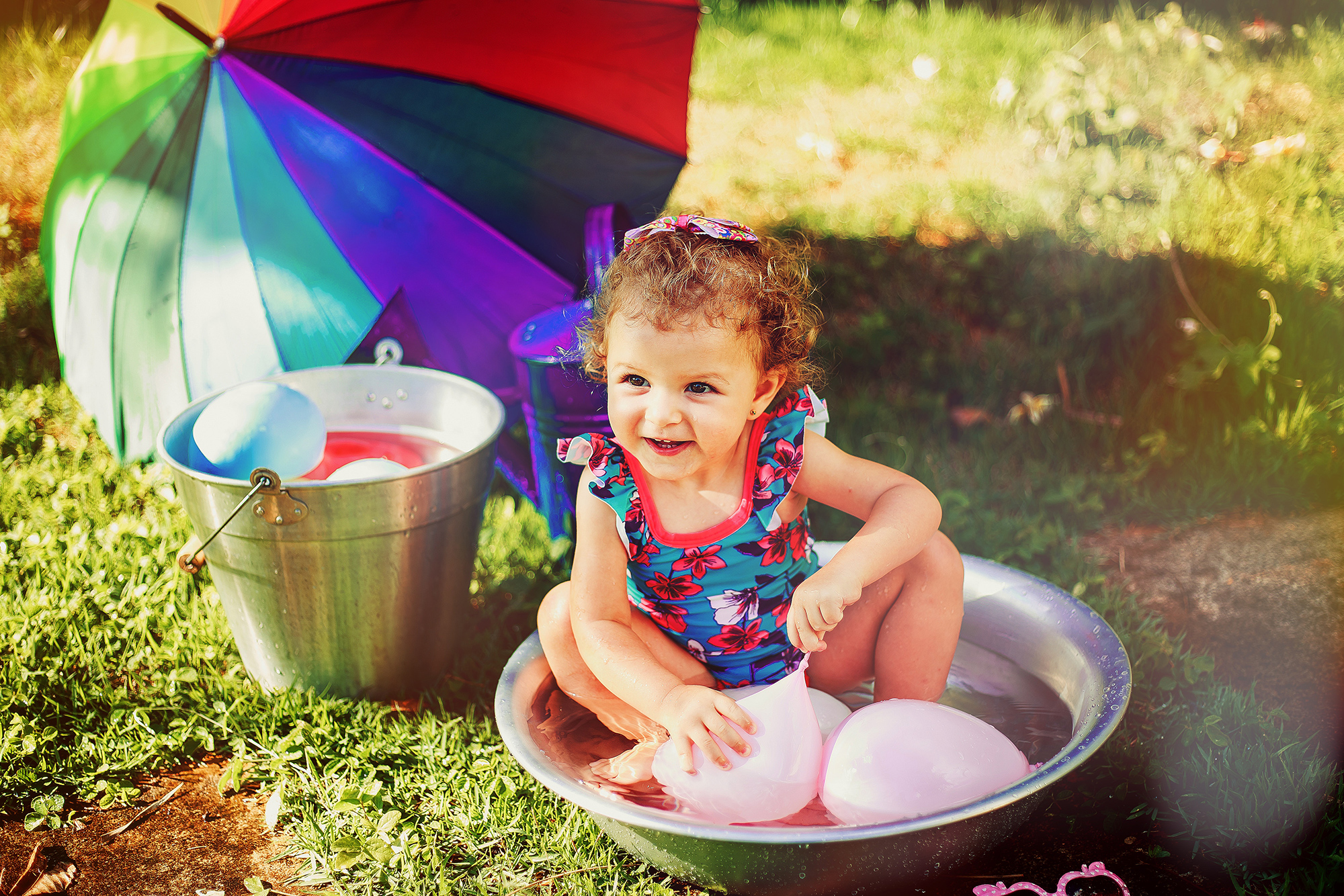 Little girl laughing playing in bucket with water ballons