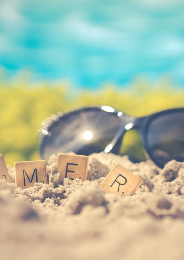 scrabble letters spelling out summer in the beach sand