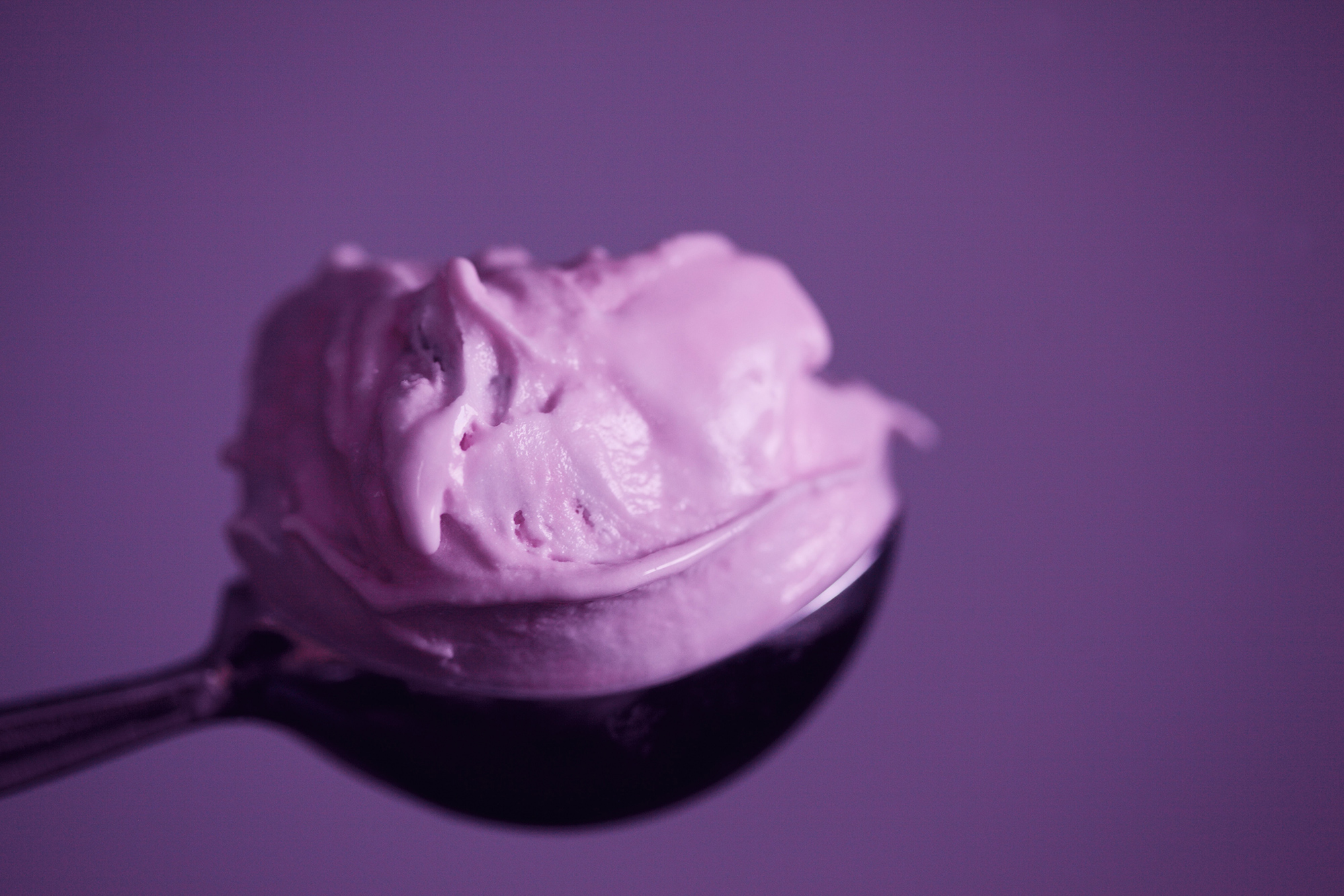 purple ice cream on a spoon with a purple background