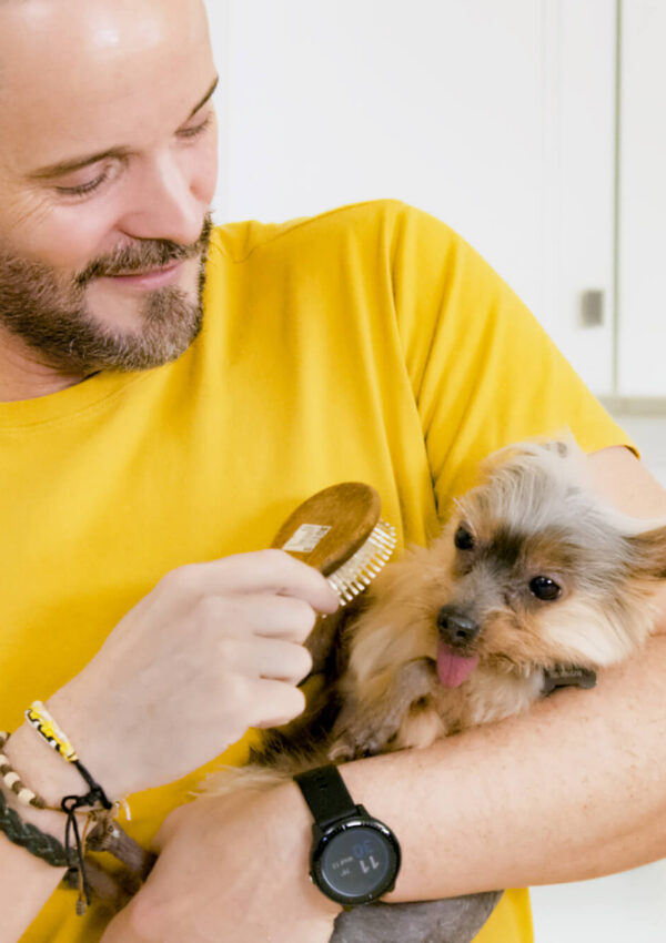 Man grooming his dog while it lays in his hands