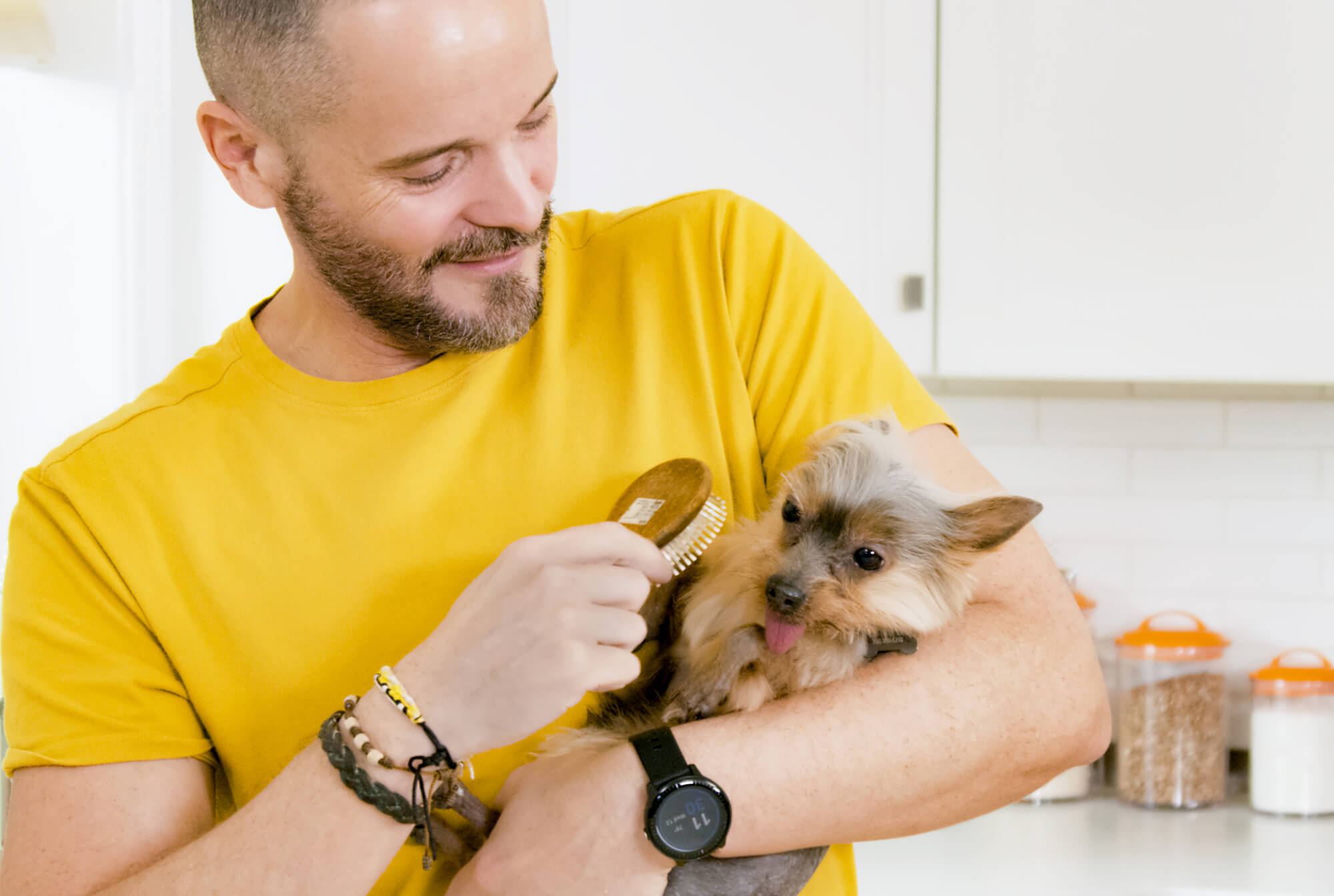 Man grooming his dog while it lays in his hands