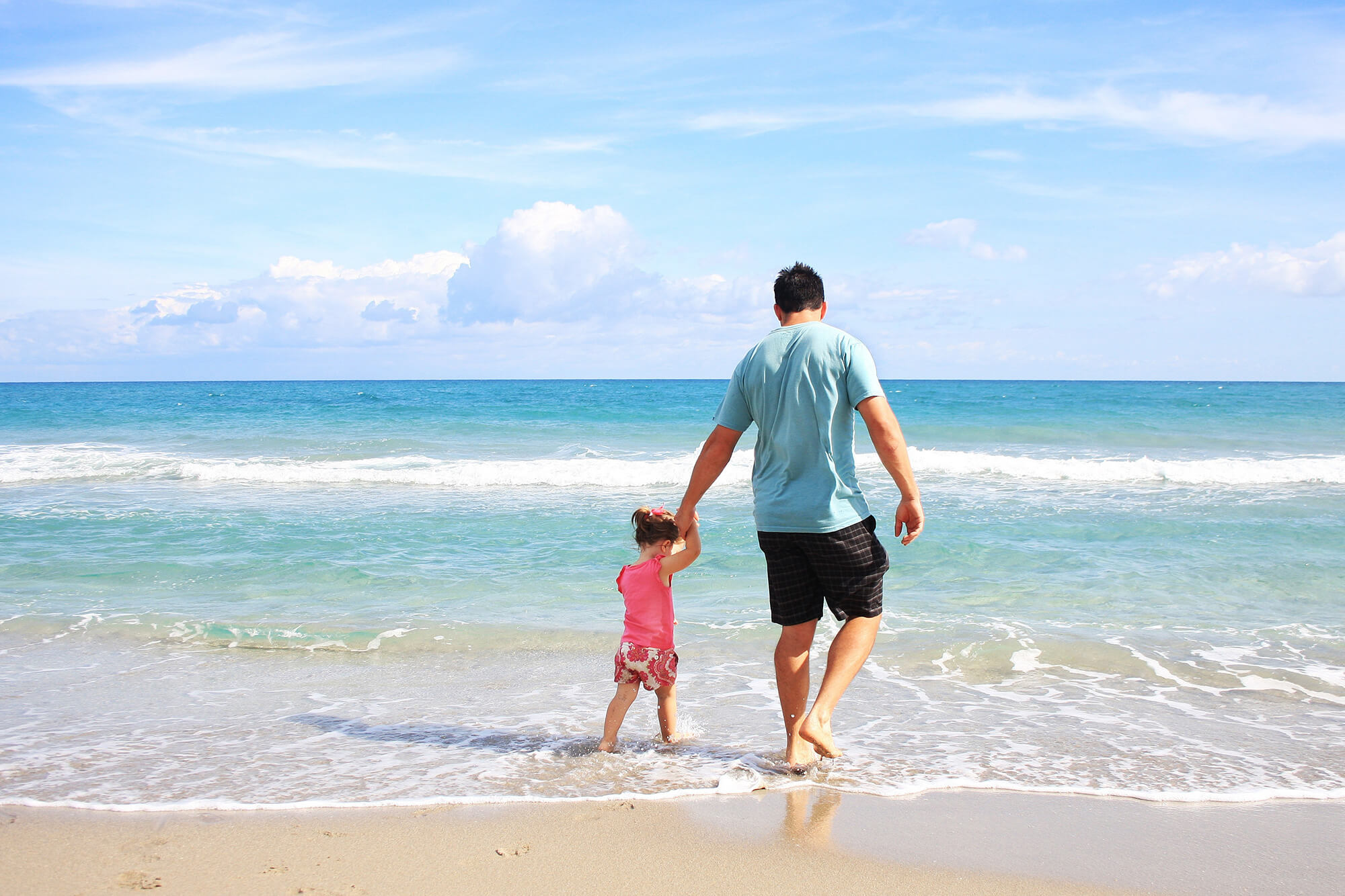 father walking on beach with toddler
