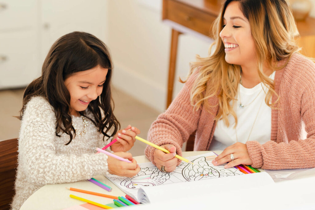 Mother and daughter drawing on table smiling