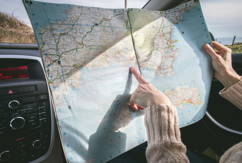 Person pointing out location on a map while in a car on a roadtrip