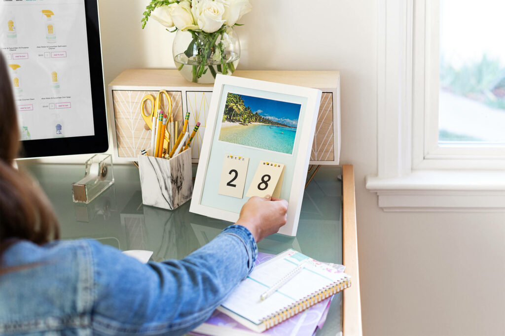 Woman flipping the date on the calendar with Scentsy products pulled up on her computer