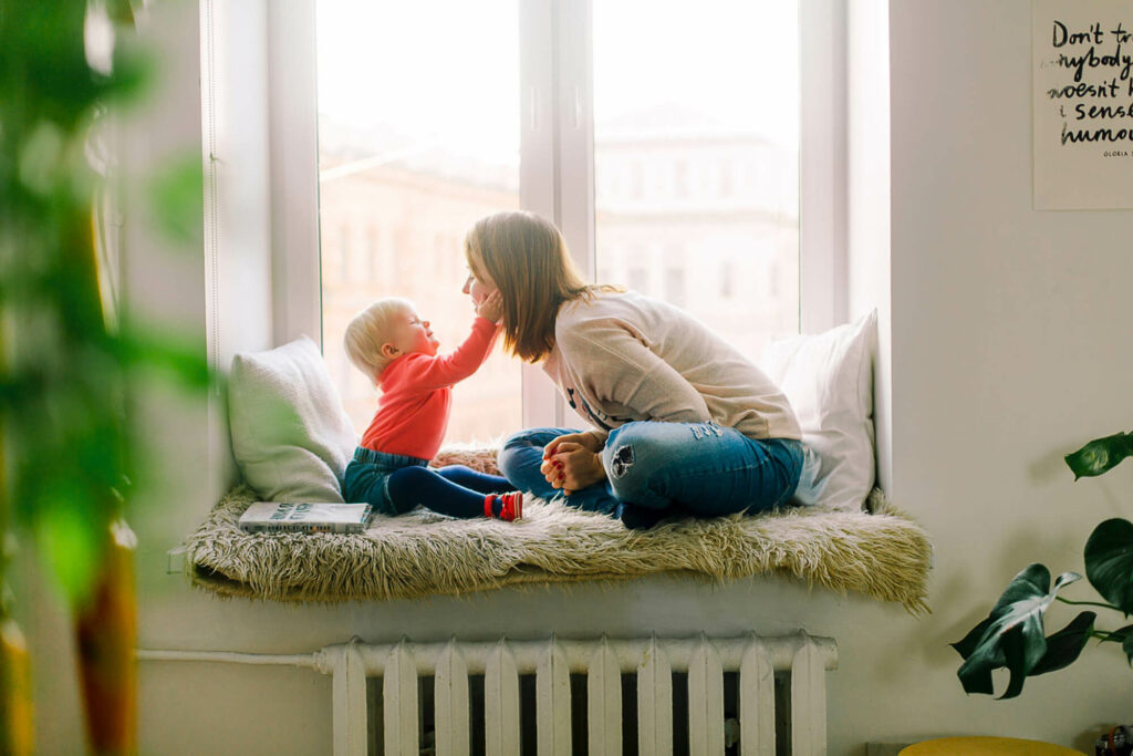 Mother playing with her child on a window sill