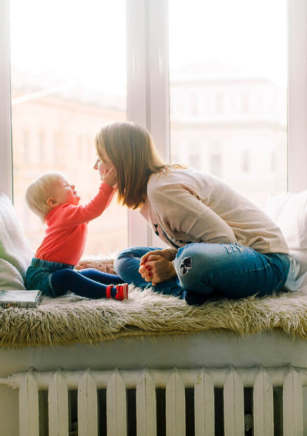 Mother playing with her child on a window sill