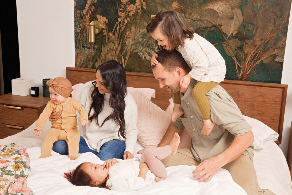 Family of five playing on the parents bed together