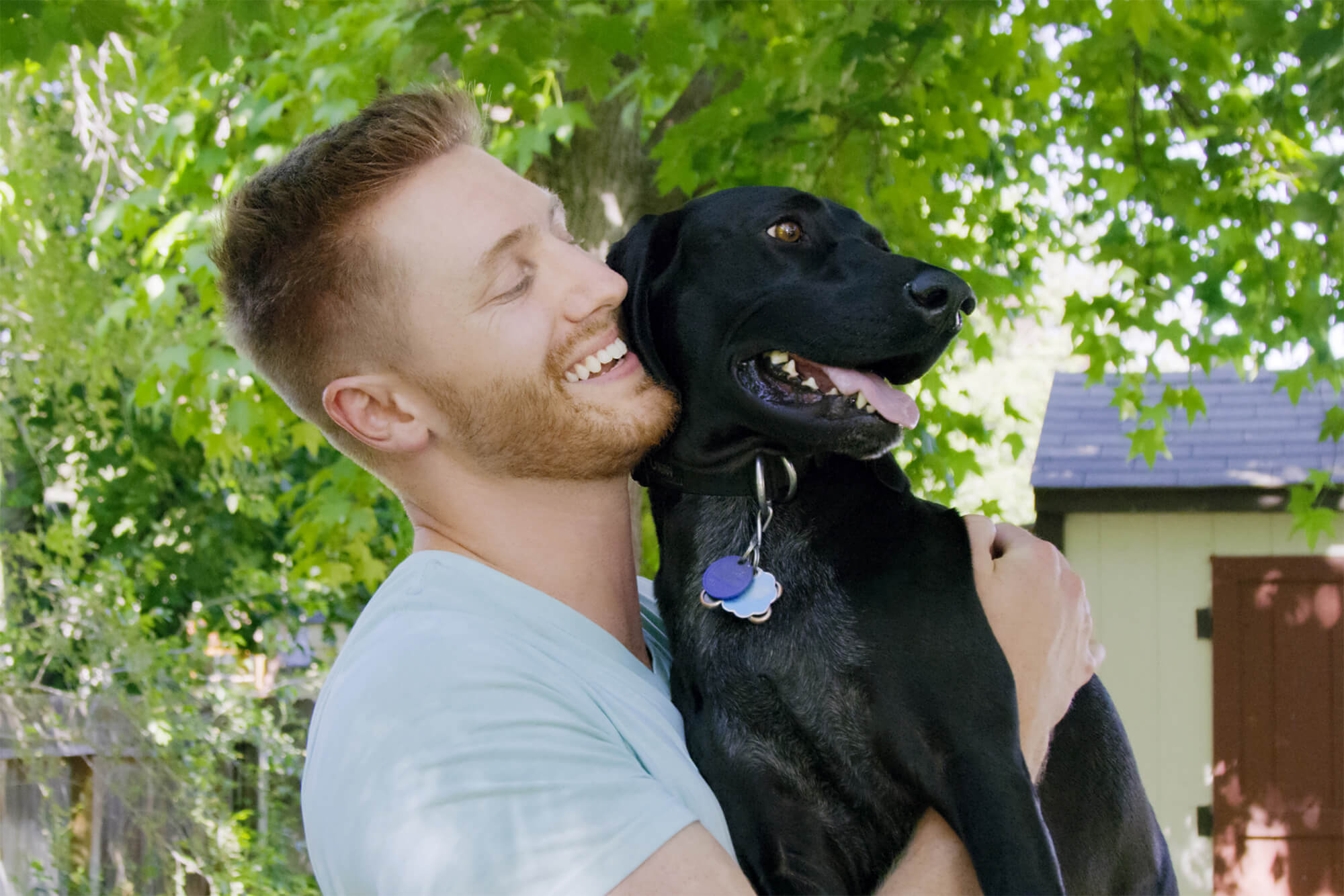Man holding his dog and smiling