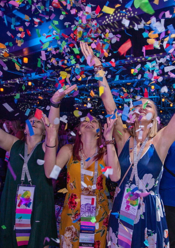 Three women tossing confetti up into the air during Scentsy Family Reunion