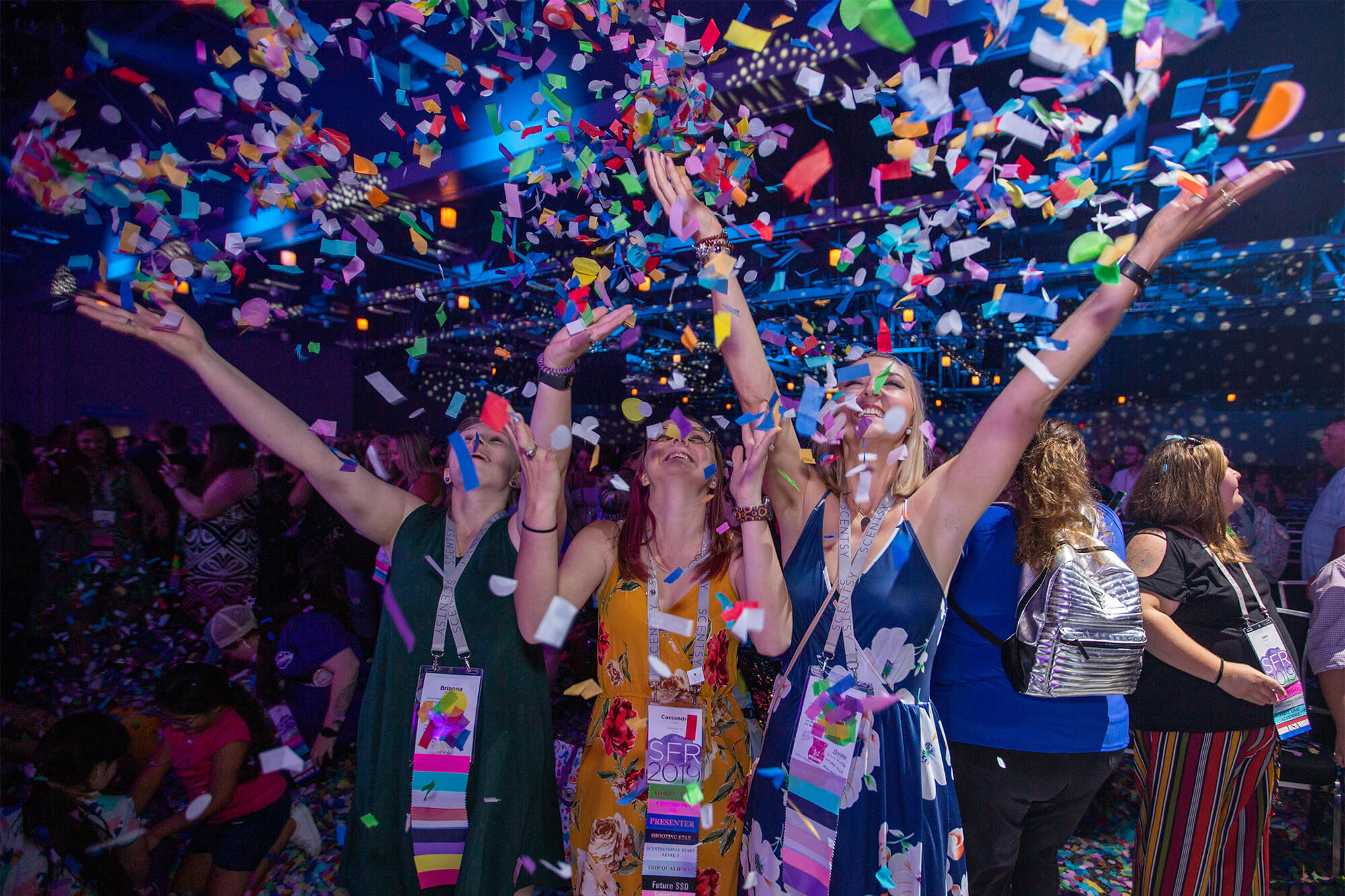 Three women tossing confetti up into the air during Scentsy Family Reunion