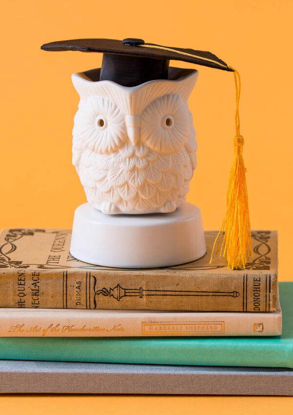 Scentsy Whoot! Mini Warmer on a stack of books with a graduation cap on
