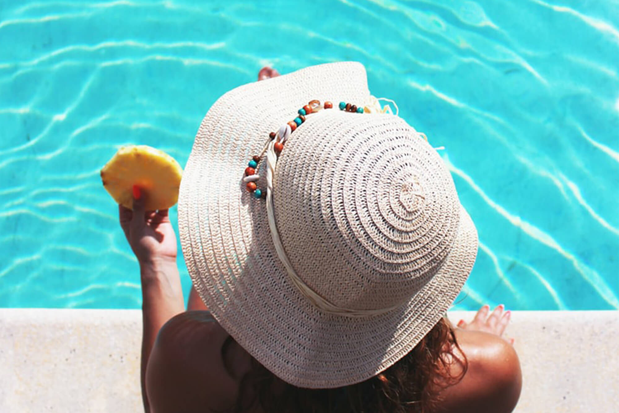 Woman relaxing by a poolside with a slice of pineapple