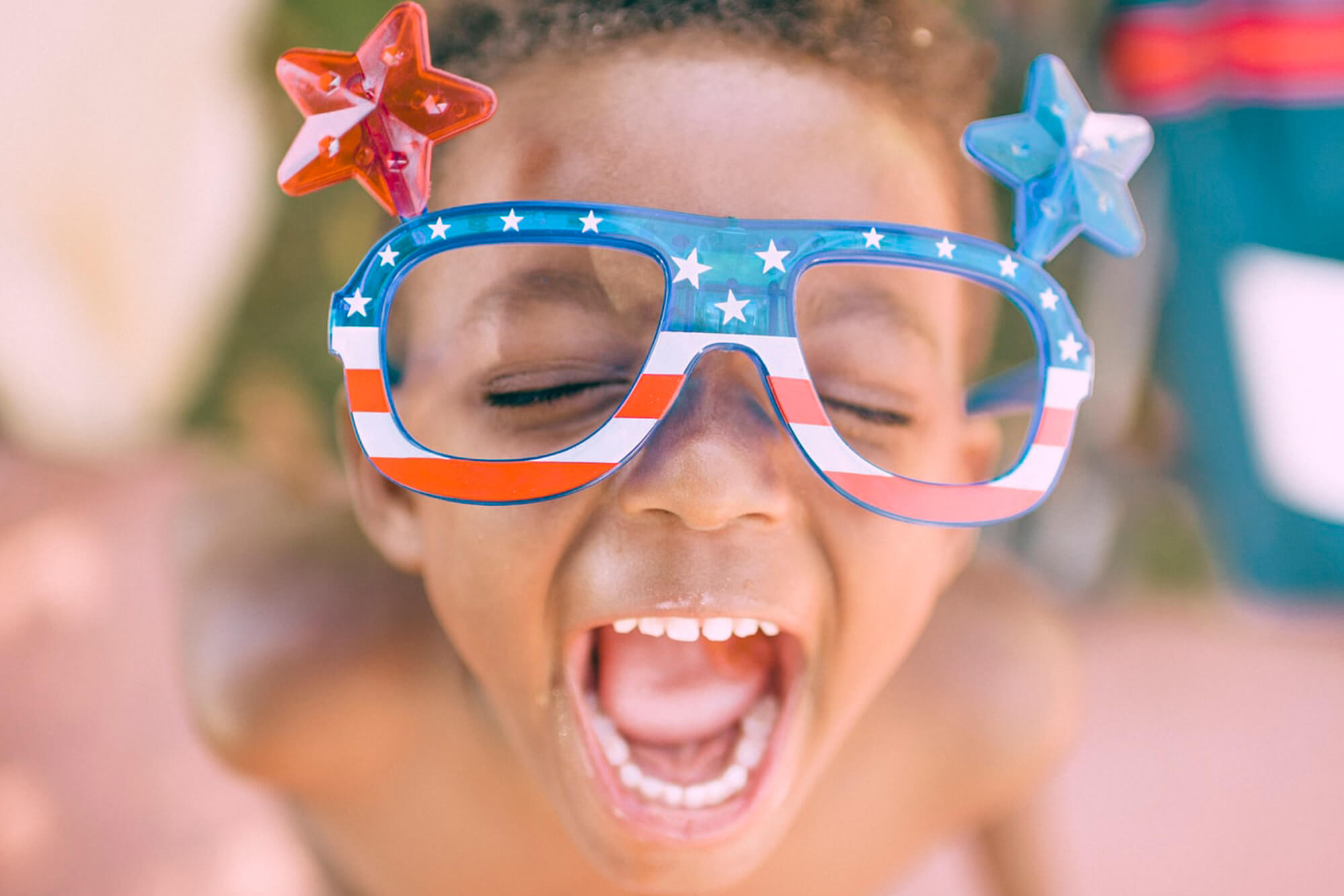 Child happily yelling with American flag glasses adorned with stars