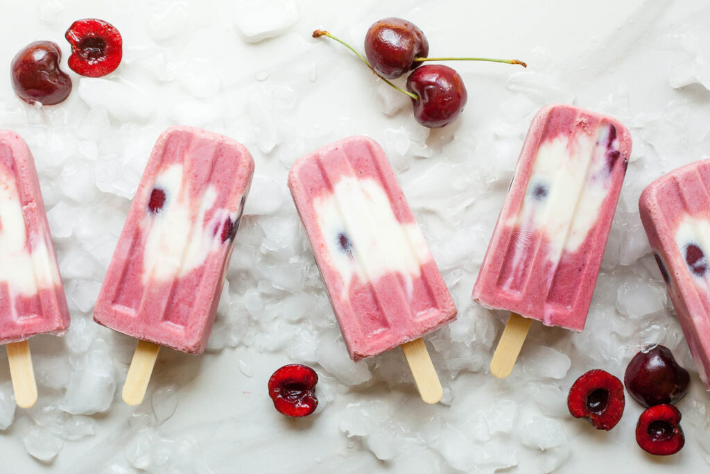 Homemade fruit pops surrounded by cherries