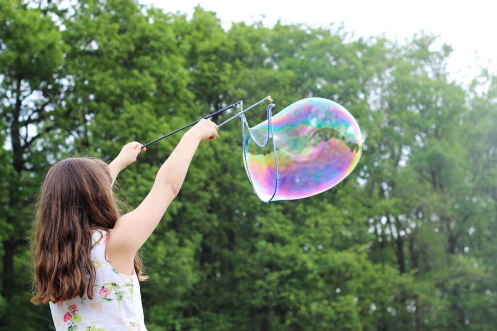 Girl making giant bubble in a park