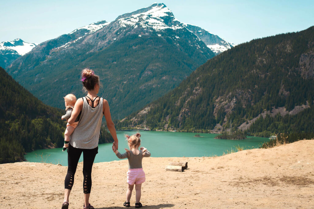 Mother and children looking out on a lake surrounded by snowy mountains