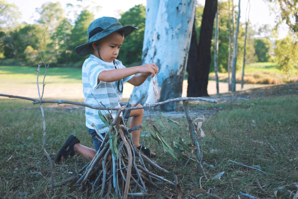 Child playing with sticks to form a teepee
