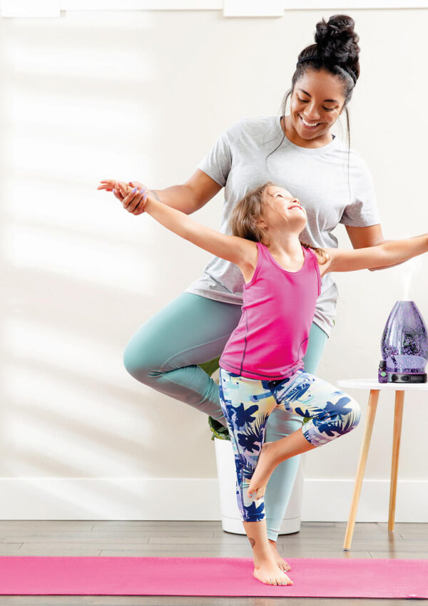 Mother and daughter doing yoga with a Scentsy diffuser in the background
