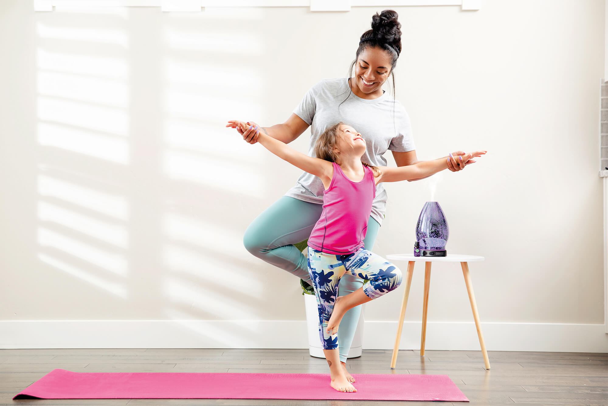 Mother and daughter doing yoga with a Scentsy diffuser in the background