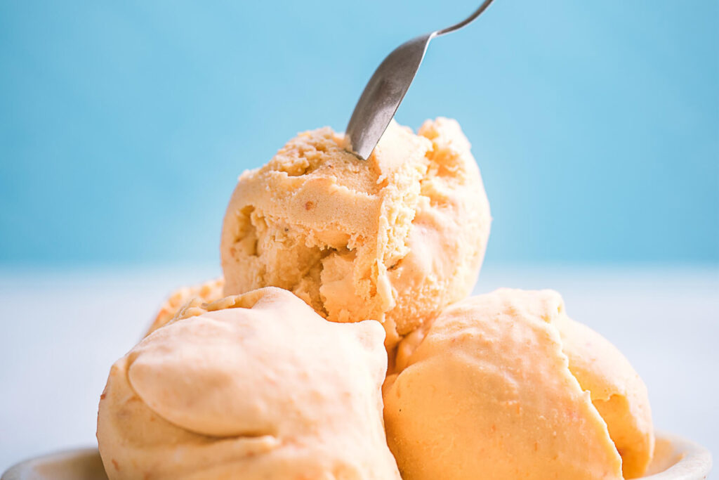 Three scoops of ice cream with a spoon in the top scoop