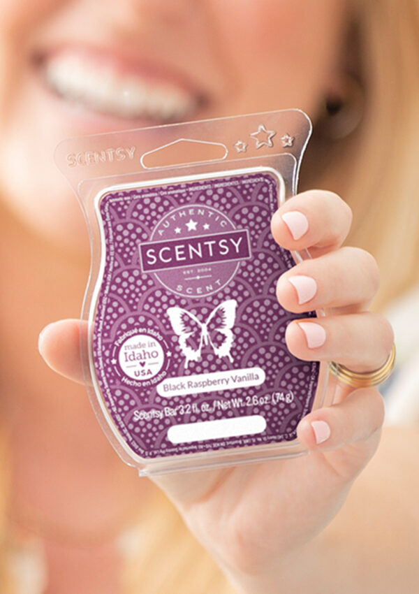 Person smiling while holding Scentsy Black Raspberry Vanilla Wax Bar up to camera