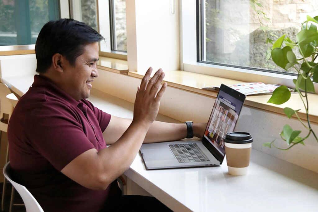 Person waving to their laptop during a Zoom call