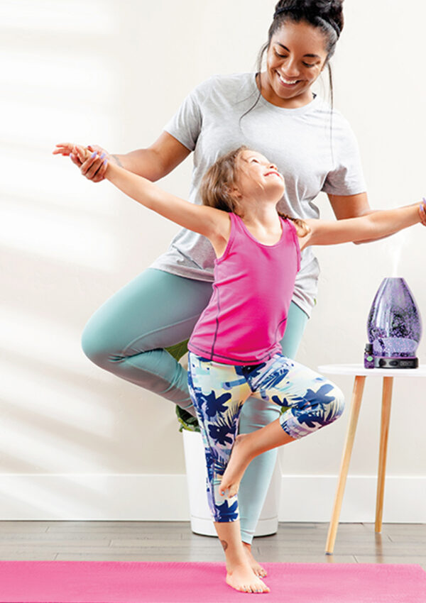 Mother and daughter doing yoga with a Scentsy diffuser in the background on a small table