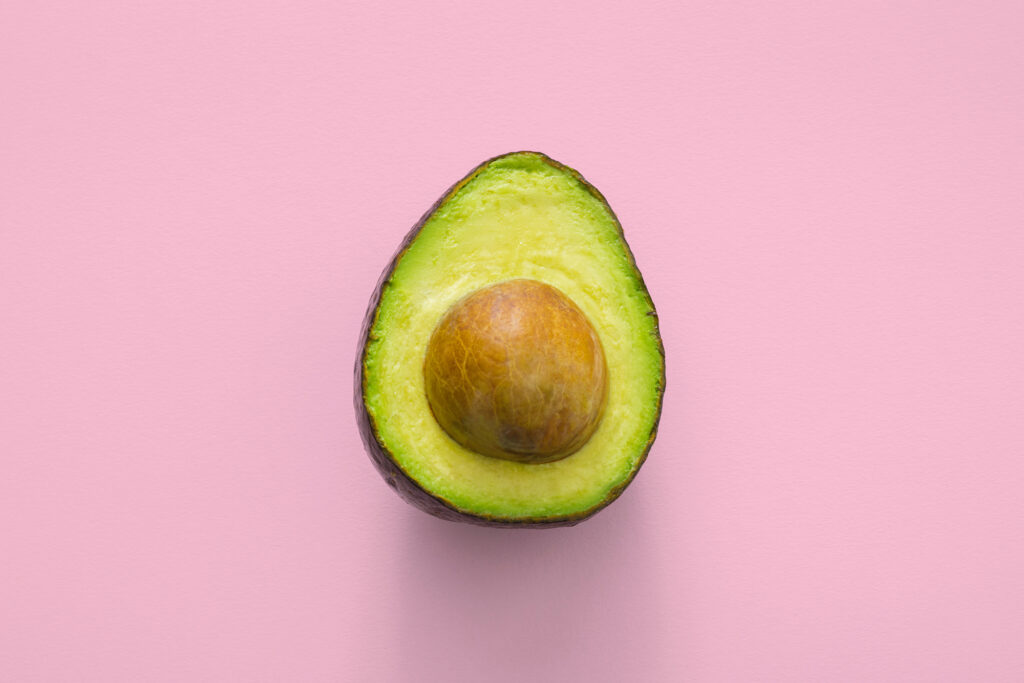 Half of an avocado on a pink background