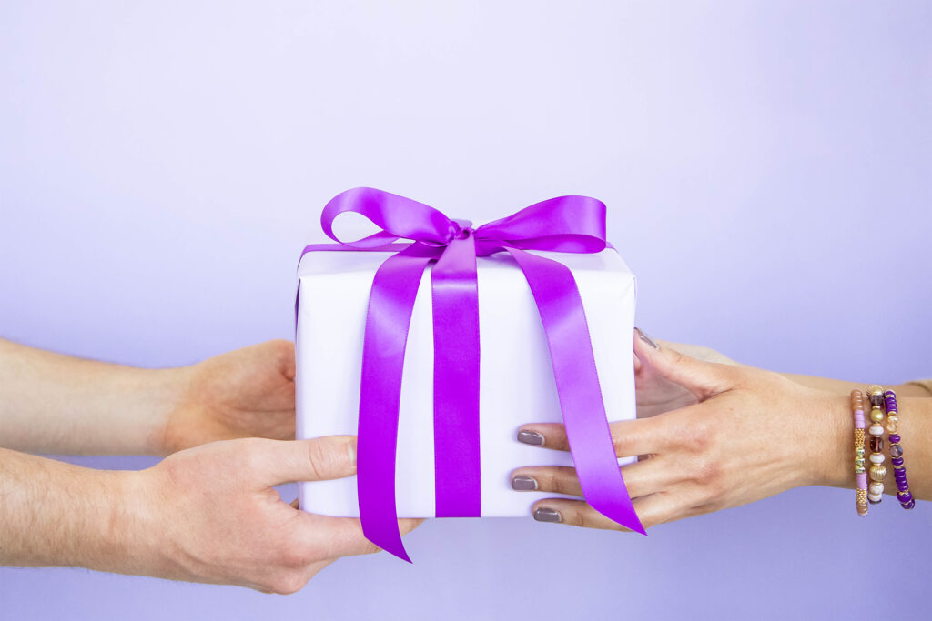 Person handing a gift to another person with a violet background