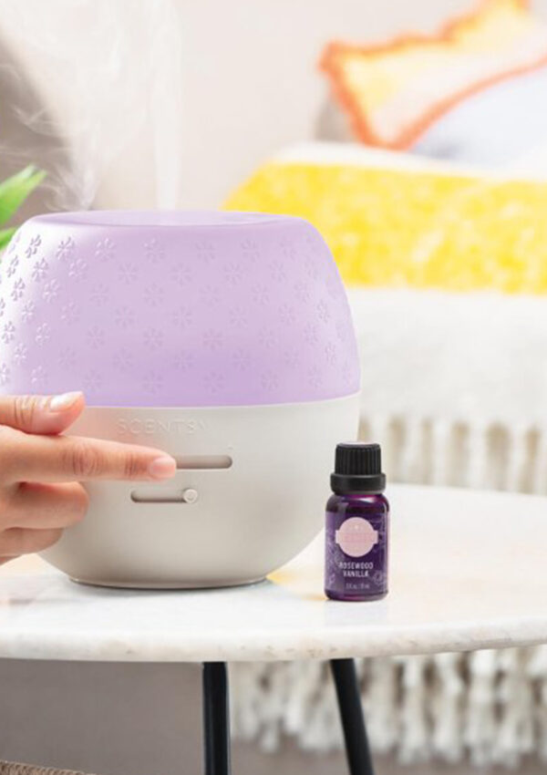 Scentsy's Deluxe Diffuser being switched on by a person off screen on a side table