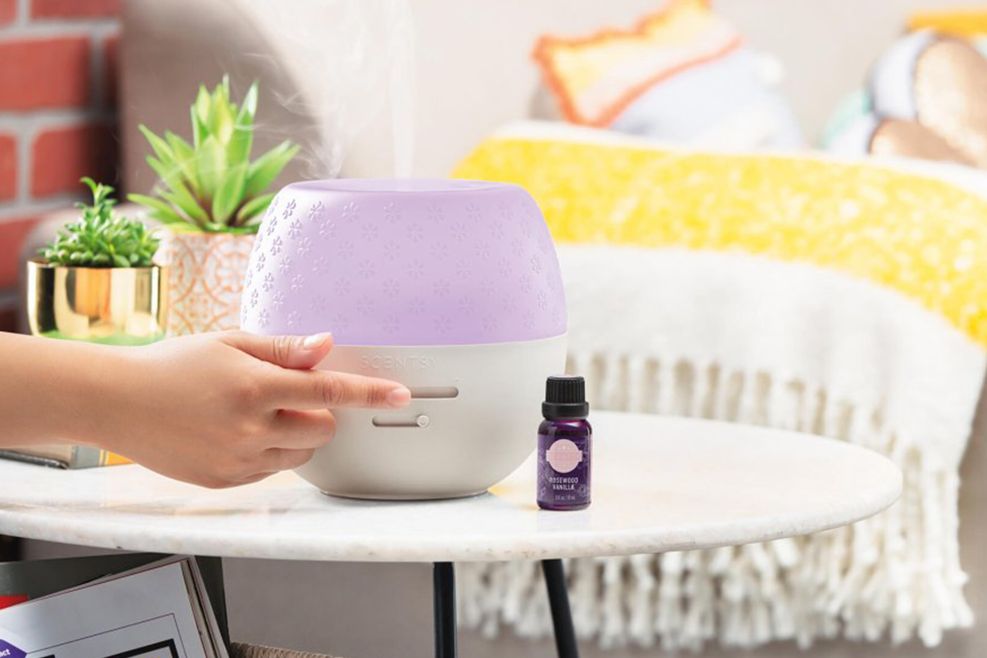 Scentsy's Deluxe Diffuser being switched on by a person off screen on a side table