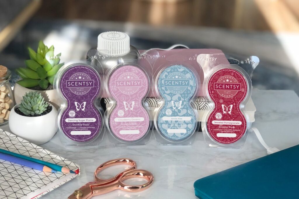 Scentsy Pods lined up on a desk, displayed next to journaling and scrapbooking materials.