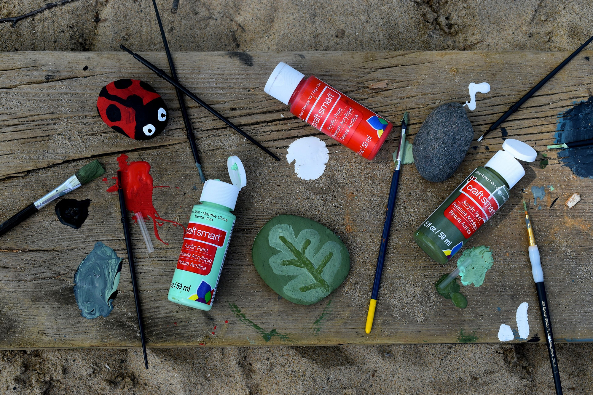 Paint and brushes scattered around with painted rocks