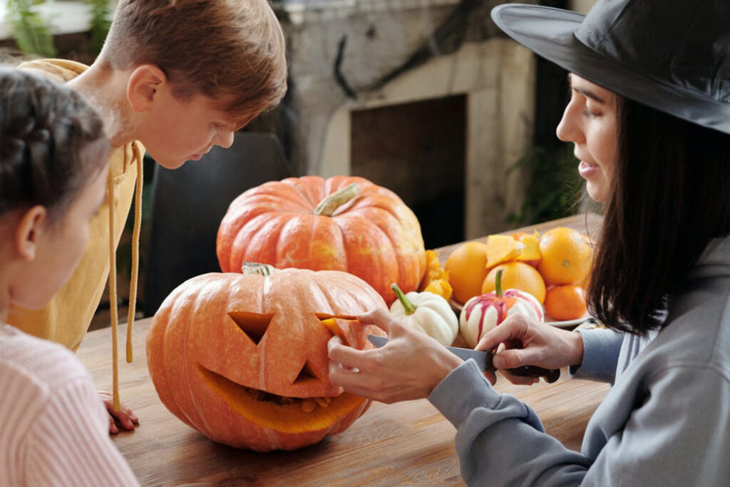 Adult and two small children carving pumpkins together
