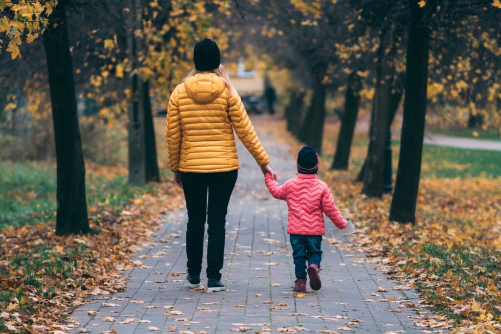 An adult and young child walking through a park