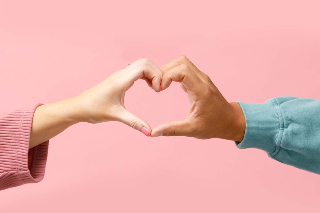 Two people putting their hands together to make a heart