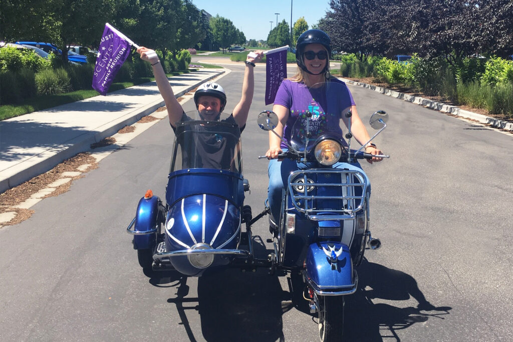 Scentsy podcast hosts riding on a motorcycle and sidecar